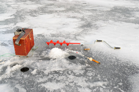 Fishing tackle for ice fishing such as a boer, fishing rod and box near the ice-hole on iceの写真素材