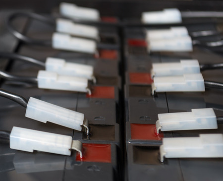 Industrial battery block hooked up with red and black cables. Close up view from side with selective focus on bottom partの写真素材