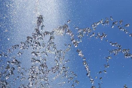 Splashes of water from the fountain against the blue sky. Freeze motion effect with fast shutter speedの写真素材