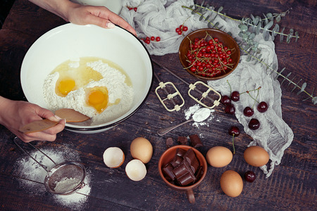 Baking background with ingredients for fruit and chocolate cake in rustic kitchen.Eggs, flour, chocolate, milk, berriesの写真素材