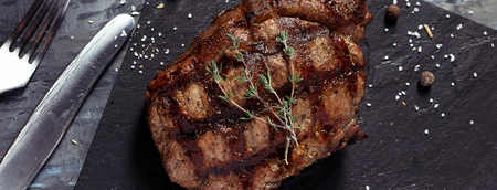 Closeup of medium rare roast beef steak with herbs, pepper and salt, cover template for social networksの写真素材