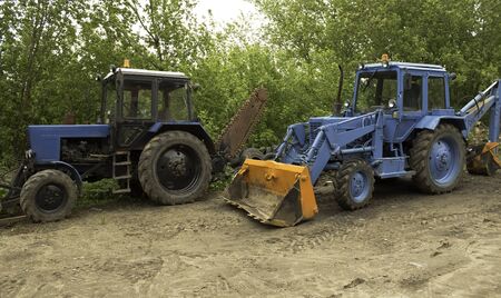 two blue tractors with various attachmentsの写真素材