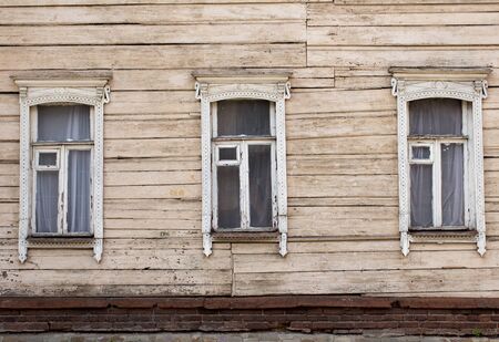 three windows decorated with carved aprons on a wooden wallの写真素材