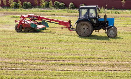 blue tractor mowing the meadow, blured in motionの写真素材