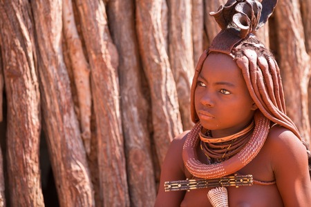 EPUPA, NAMIBIA - AUGUST 4: An unidentified Himba woman stands while tourists visit the the himba settlement on August 4, 2013 in Namibiaのeditorial素材