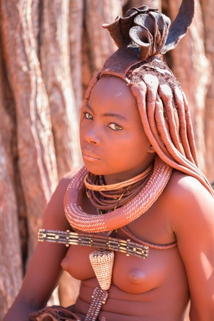 EPUPA, NAMIBIA - AUGUST 4: An unidentified Himba woman standing while tourists visit the the himba...