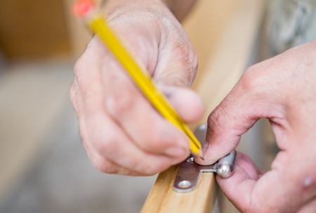 Closeup of carpenter with pencil working on doorの写真素材