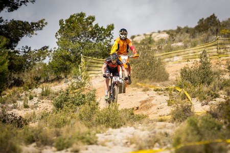 VALENCIA - MARCH 6: Unidentified rider descends behind motorbike in international Chelva MTB-XCO competition in Chelva on march 6, 2016 in Valencia, Spainのeditorial素材