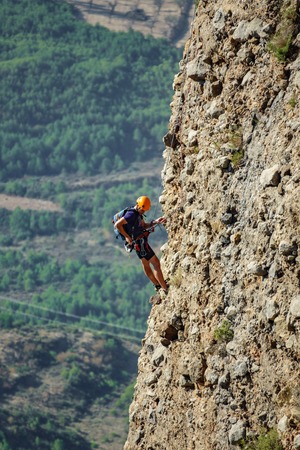 Blurred male climber hanging by a cliffの写真素材