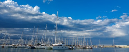 Marina with sailing ships and cloudy sky