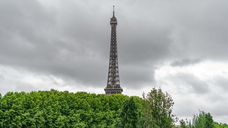 The Eiffel Tower rocket over the trees with stormy clouds
