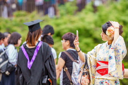 KYOTO, JAPAN- JUNE 8, 2015: Unidentified Japanese woman takes selfie with mobile phone dressed in...