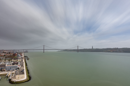Wide top view 25 de Abril Bridge in Lisbon over Tagus river, ultra long exposure