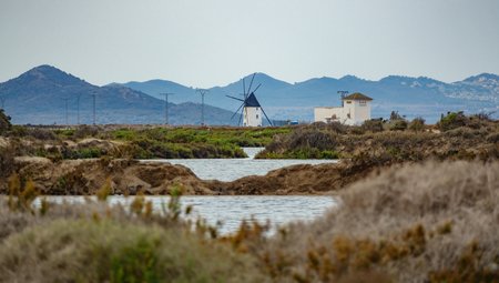 Antique windmill near water with mountain range in the backgroundの写真素材