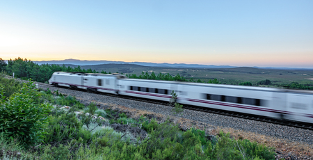 Railway and blurred fast train against clear blue skyの写真素材
