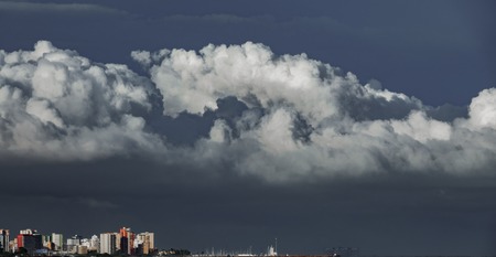 Long shot of skyscrappers near sea with stormy cloudsの写真素材