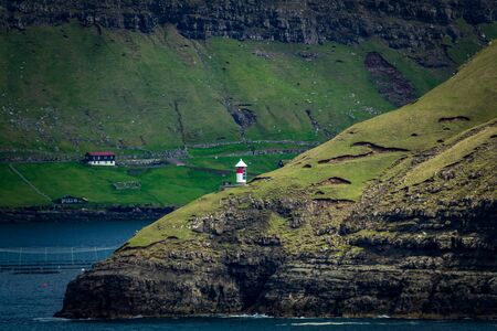 Isolated autonomous small lighthouse in Faroe Islands coastの写真素材