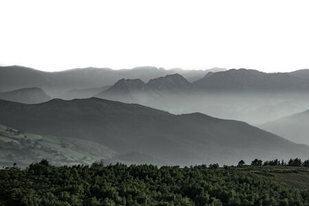 Mist over the mountains with white skyの写真素材