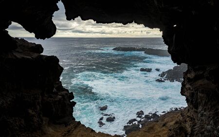 Hole to the pacific ocean from the inside of lava caveの写真素材