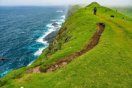 Narrow path in Mykines islannd with touristsの写真素材