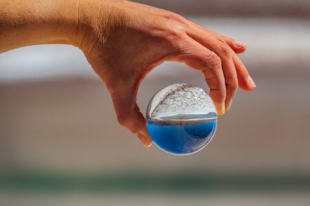 Hand holding glass ball over salt lake in Atacamaの写真素材