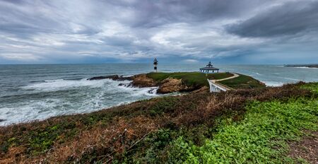 Lighthouse in the islet under stormy skyの写真素材