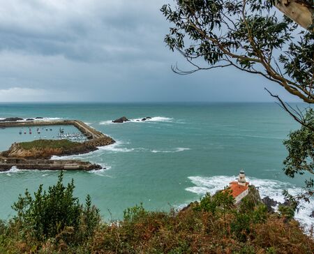 Lighthouse and marina under stormy cloudy skyの写真素材