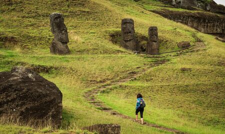 Unrecognizable tourist woman hiking along moais in rpa nuiの写真素材