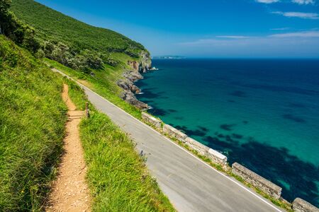 Hiking track and road near the sheer coastlineの写真素材