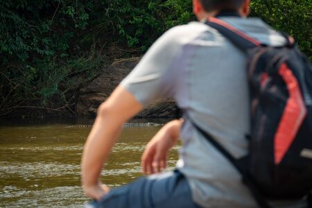 Rear view of tourist at river shore looking at crocodileの写真素材