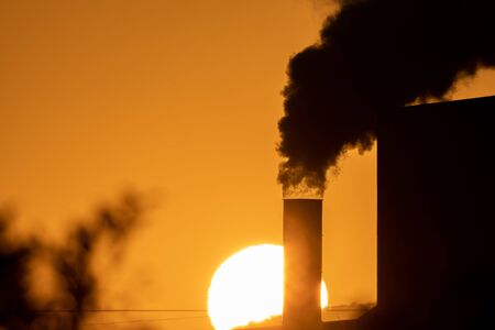 Tube with black smoke and huge sunset in the backgroundの写真素材