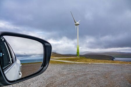 Car mirror with ocean and windmill under cloudy sky with text spaceの写真素材