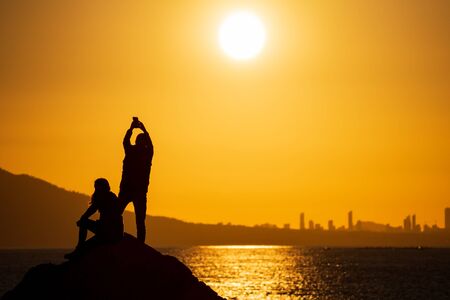 Couple taking photos at sunset over city skylineの写真素材