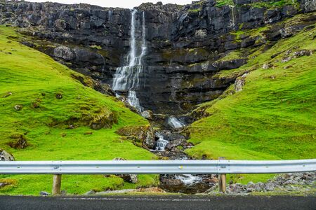 Waterfall over the rocks near the roadの写真素材