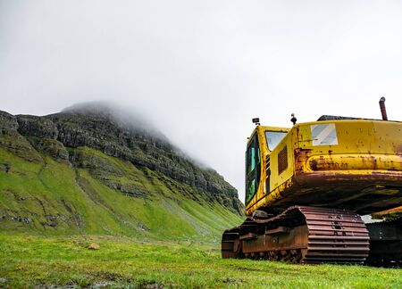 Abandoned heavy machine in the hillside under white skyの写真素材