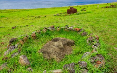 Moai buried on the ground surrounded with stonesの写真素材