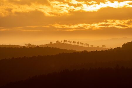 Sunset with orange sky and many hills in layersの写真素材
