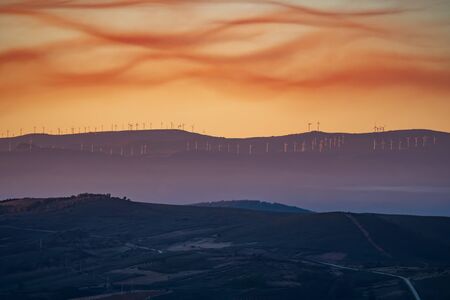 Countryside with windmills in the background and cloudy sky at sunsetの写真素材