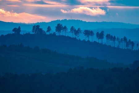 Sunset with orange sky and many bluish hills in layersの写真素材