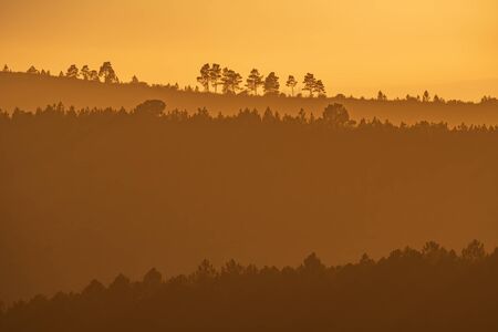 Sunset with orange sky and many layered hillsの写真素材