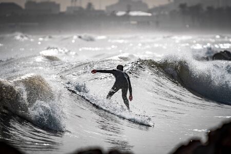 High contrast of unrecognizable surfer surfing near the cityの写真素材