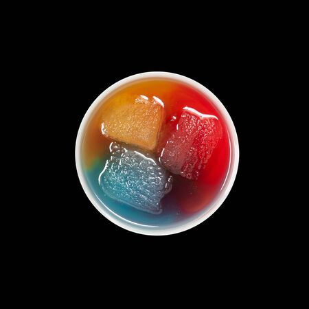 Top view of bowl with ice melting in primary colors on blackの写真素材
