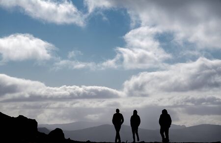 Tree unrecognizable people silhouettes walking on top of the mountain at duskの写真素材