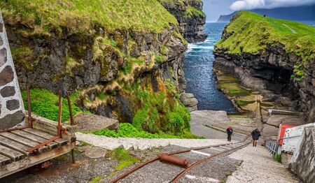 Gjogv harbour and unrecognizable tourists in Faroe islandsの写真素材