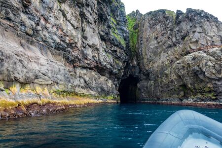 Rubber motorboat sailing to the dark caveの写真素材