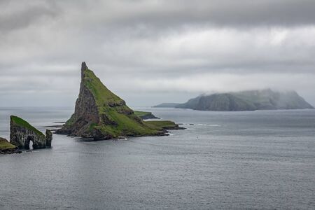 Amazing wide view of Drangarnir gate, Tindholmur and Mykines under the cloudsの写真素材