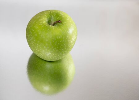 Bright green apple isolated and reflected, closeupの写真素材