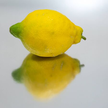 Bright yellow lemon isolated and reflectedの写真素材