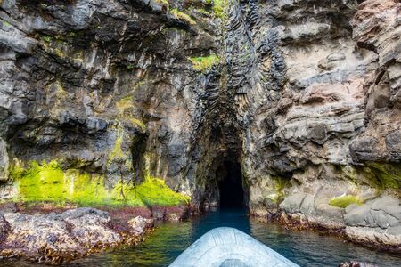 Rubber boat entering dark cave near the oceanの写真素材