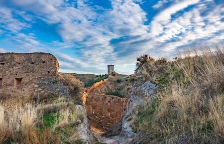 Ancient rebuilt tower with ruined walls aroundの写真素材
